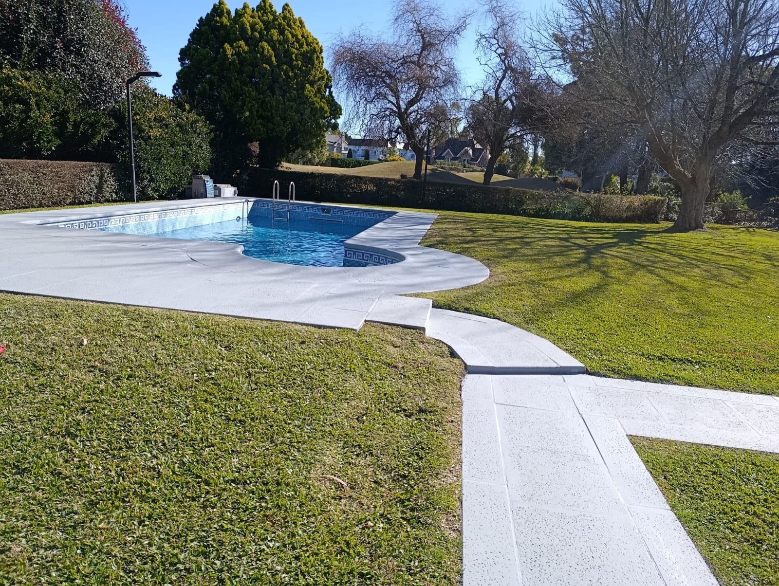 Piscina de hormigón de líneas curvas terminada, en un barrio cerrado