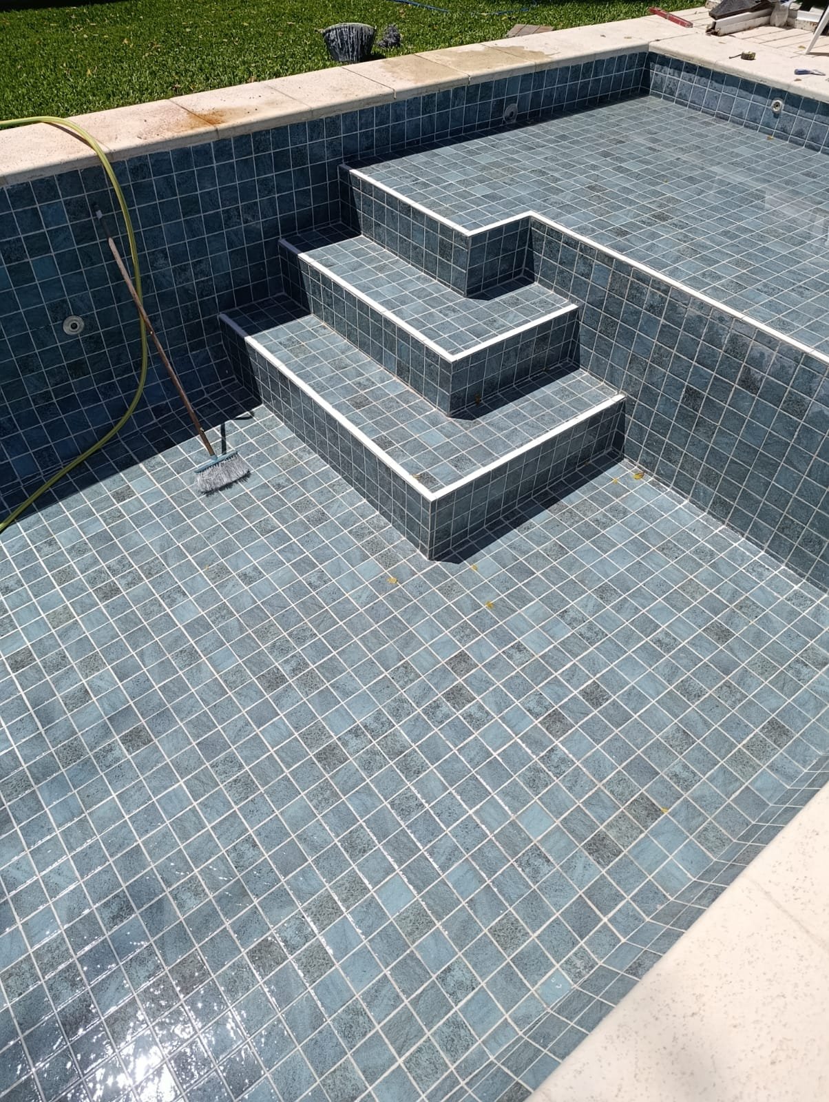 Detalle de los escalones de mosaico de una piscina de hormigón, en una vivienda particular
